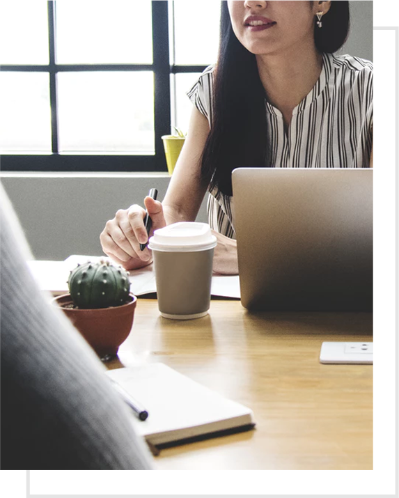 woman behind a laptop having a discussion with someone else across a table